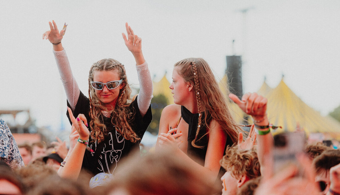 2 Fans raising arms while on their friends shoulders at Leeds Festival