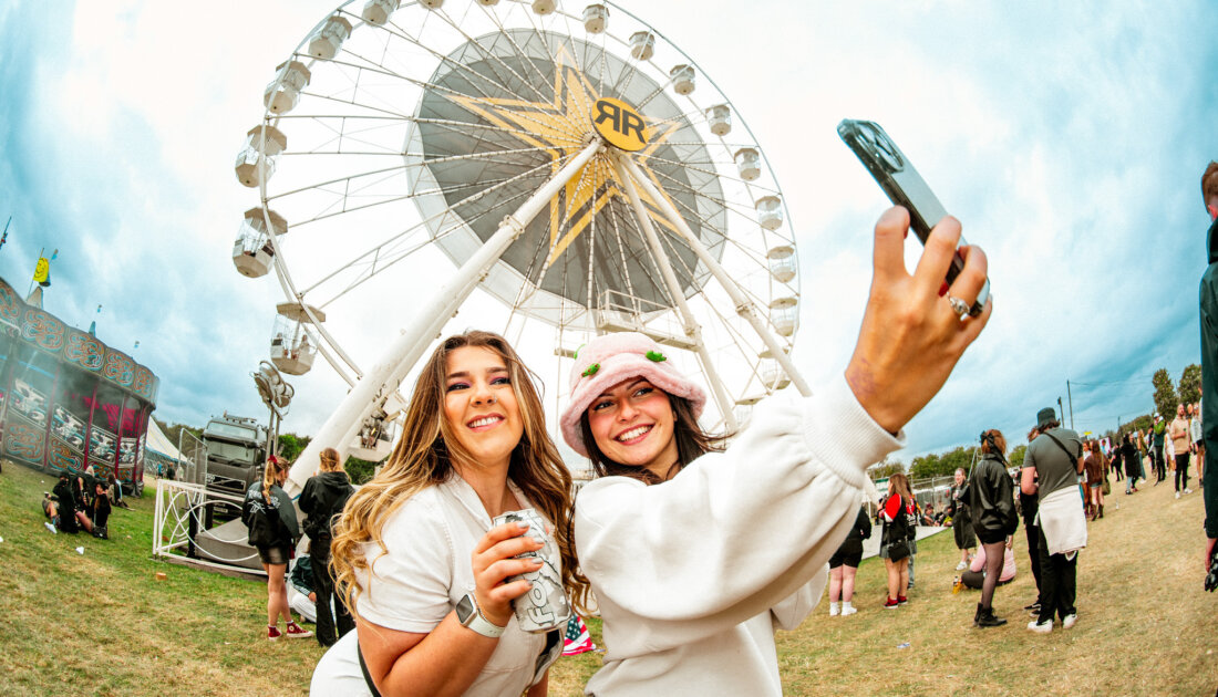 Fans taking a selfie standing by ferris wheel at Leeds Festival