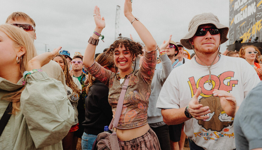 Fan raising their arms and smiling in photo at Mainstage at Leeds Festival